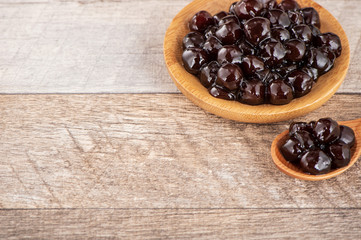 Tapioca Pearl , Bubble topping for tea or other beverage, in a cup, place on wooden table. Copy space