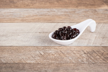 Tapioca Pearl , Bubble topping for tea or other beverage, in a cup, place on wooden table. Copy space