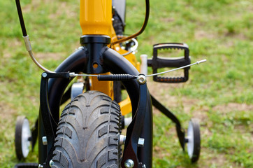 Kids yellow bicycle in park, close up parts, front tire with brakes