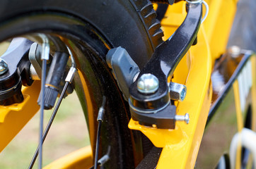 Kids yellow bicycle in park, close up parts, rear tire with brakes