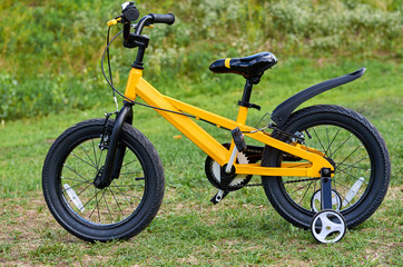 Kids yellow bicycle in park, close up parts