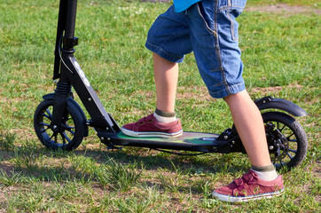 Kid in casual wear on kick scooter in park