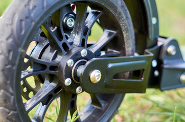 Black folding kick scooter, close up parts, rear wheel