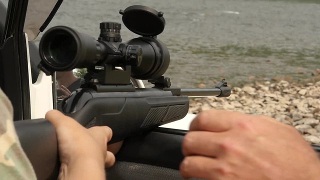 Man shooting an air rifle gun with optical sight during a vacation on a wild nature. slow motion