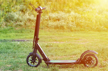 Black folding kick scooter, close up parts, sunlight effect