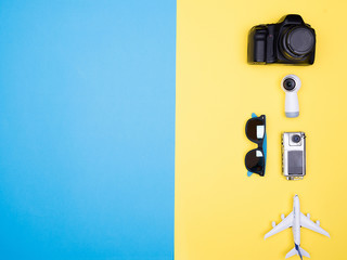 Flat lay top view of plane on yellow background. next to sunglasses and camera