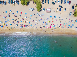 Luftaufnahme eines überfüllten Strandes and der Südküste von Athen mit bunten Sonnenschirmen und zahlreichen Leuten