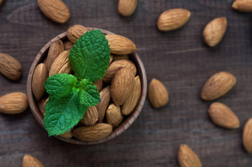 Almond in a wooden bowl with mint leaves.