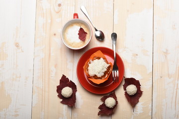 Cup of cappuccino coffee on wooden background with autumn leaves