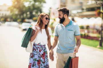 Beautiful couple enjoy shopping together, young couple holding shopping bags
