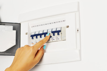 Woman turning off the switchboard of an electrical circuit panel
