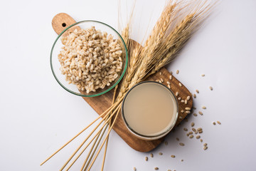 Barley water in glass with raw and cooked pearl barley wheat/seeds. selective focus
