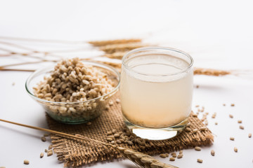 Barley water in glass with raw and cooked pearl barley wheat/seeds. selective focus