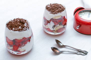 Strawberry dessert with chocolate chips, banana and sour cream in the glass.
