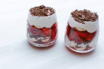 Strawberry dessert with chocolate chips, banana and sour cream in the glass.