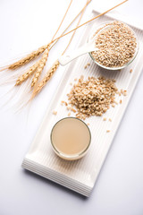 Barley water in glass with raw and cooked pearl barley wheat/seeds. selective focus