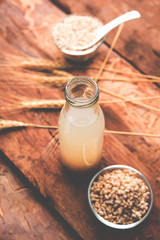 Barley water in glass bottle with raw and cooked pearl barley wheat/seeds. selective focus