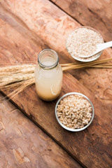 Barley water in glass bottle with raw and cooked pearl barley wheat/seeds. selective focus