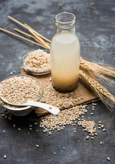 Barley water in glass bottle with raw and cooked pearl barley wheat/seeds. selective focus