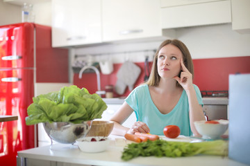 Girl sitting in the kitchen, thinking about what to prepare for lunch