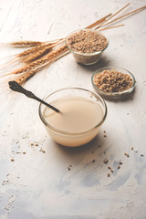 Barley water in glass bowl with spoon and raw and cooked pearl barley wheat/seeds. selective focus