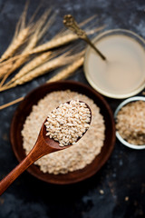 Barley water in glass bowl with spoon and raw and cooked pearl barley wheat/seeds. selective focus
