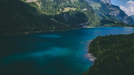 Fototapeta na wymiar aerial view of deep blue mountain lake in swiss alps, klontalersee switzerland