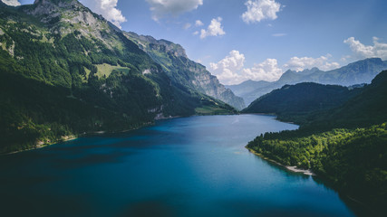 Naklejka na ściany i meble aerial view of deep blue mountain lake in swiss alps, klontalersee switzerland