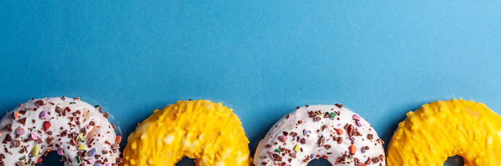 White and yellow donuts on a blue, smooth background