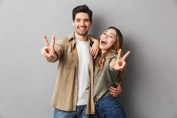 Happy young couple showing peace gesture
