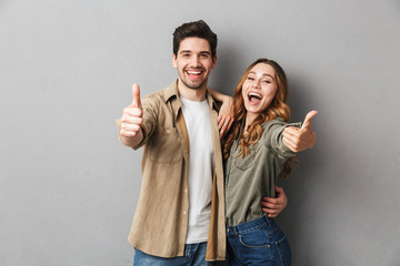 Happy young couple showing thumbs up