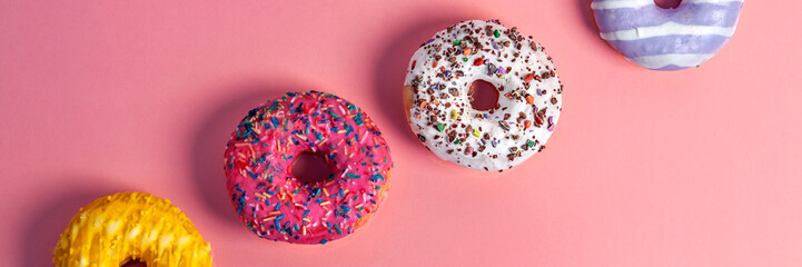 Millennial pink smooth background with colorful donuts on the diagonal