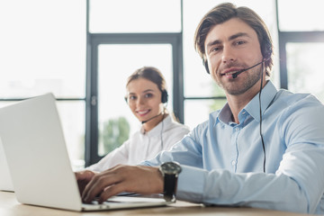male and female call center managers working together at modern office and looking at camera