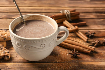 Cup of delicious hot cocoa on wooden background