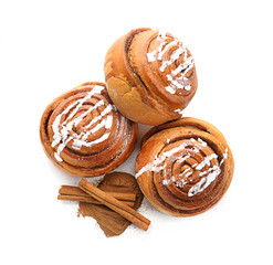 Tasty sweet buns with cinnamon sticks and powder on white background