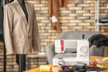 Tailor's workplace with sewing machine and mannequin in atelier