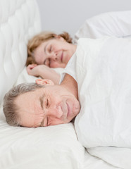 Happy elderly couple sleeping together on the bed