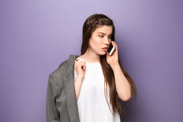 Fototapeta na wymiar Beautiful young woman talking on mobile phone against color background