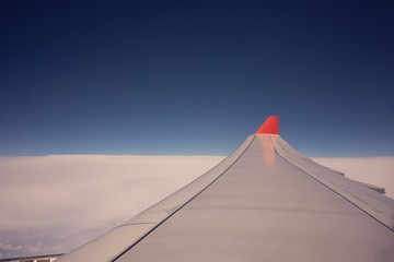 Airplane wing flying above clouds sunrise