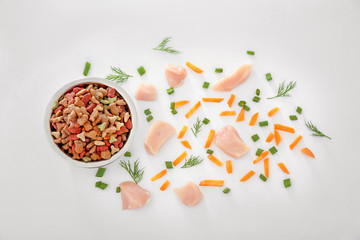 Bowl with pet food and natural products on white background