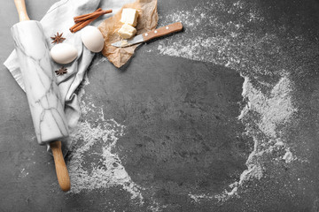 Composition with scattered flour, rolling pin and ingredients on grey background