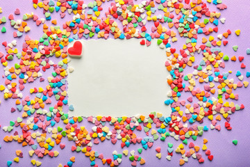 Blank card and different heart-shaped candies on color background