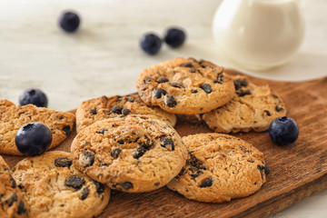 Delicious chocolate chip cookies with fresh blueberries on wooden board