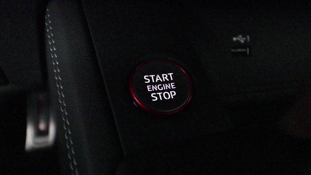 Finger pushing start engine backlit button very dark close up
