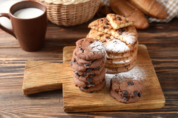 Board with delicious chocolate chip cookies on wooden table