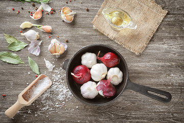 Composition with red onions, garlic and spices on wooden background