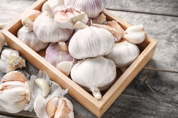Crate with fresh garlic on wooden background
