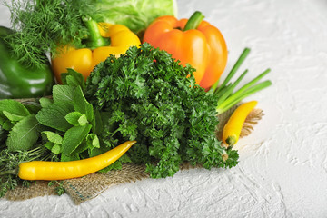 Composition with different fresh herbs and vegetables on light background