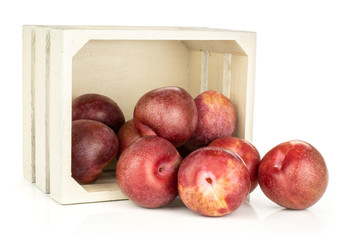 Lot of whole fresh pluot interspecific plums variety out of a natural wooden crate isolated on white