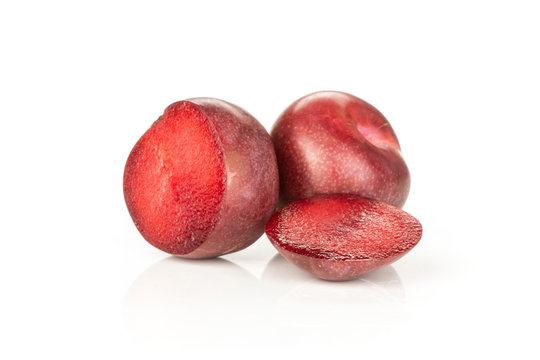 Group of one whole two halves of fresh pluot interspecific plums variety isolated on white